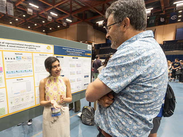 An undergraduate student explains her research findings to a faculty moderator at the 2023 research conference poster session.