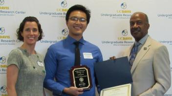 Jie (Jackson) Zhu accepts his 2019 Chancellor's Award for Excellence in Mentoring Undergraduate Research posing with Professor Annaliese Franz and Chancellor May