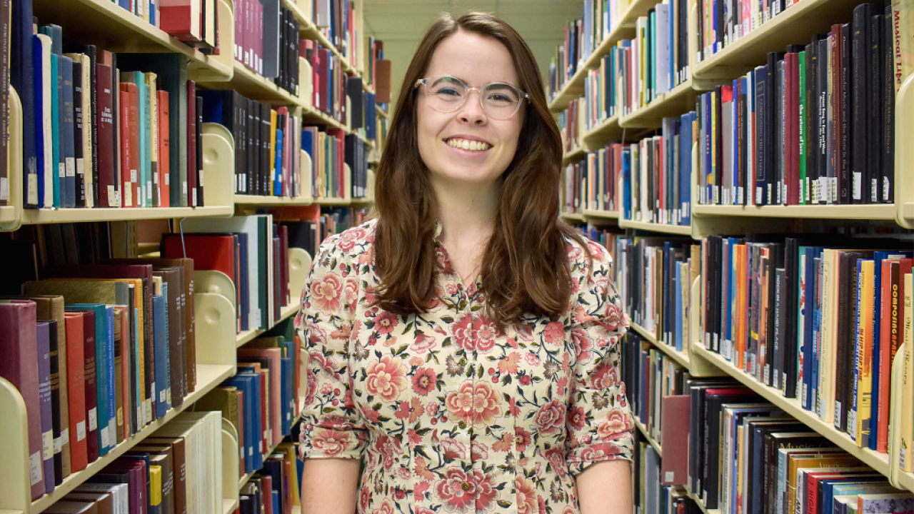 Megan West A photo of Megan west between library book shelves.
