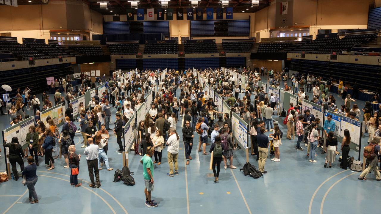 long overhead shot of URSCA conference showing crowds between rows of poster presentations and arts & Design exhibits in U Center