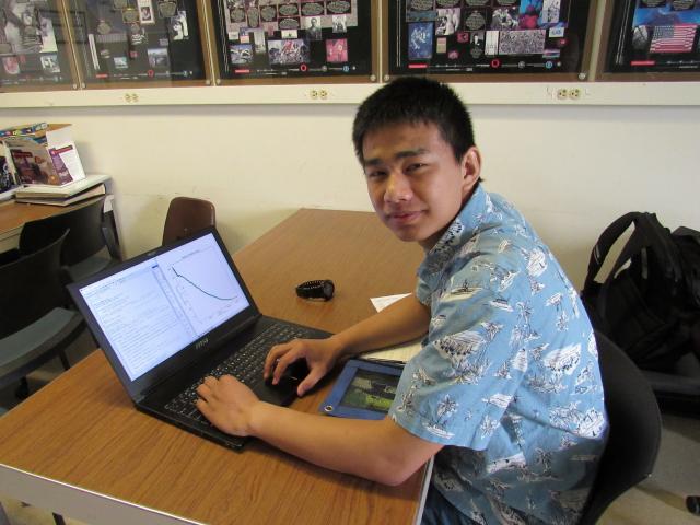 A student at a desk working on a laptop 