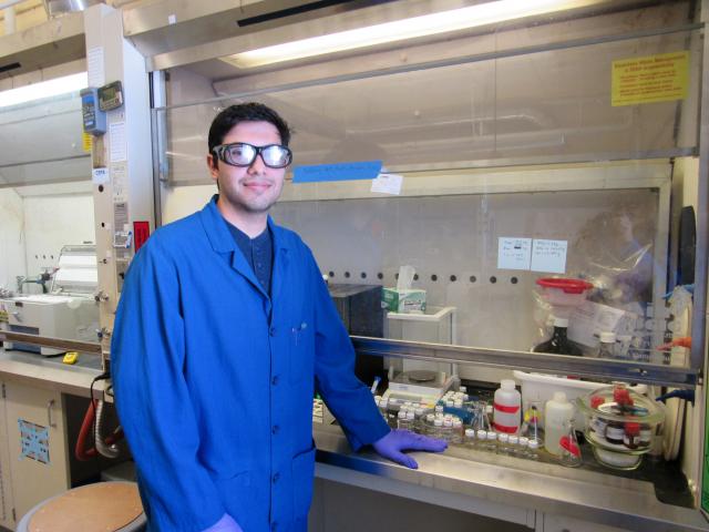 Student wearing lab coat, safety goggles and gloves in a lab