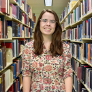 A photo of Megan west between library book shelves.