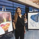 Photo of Sid Ganesh standing with two watercolor paintings at the Undergraduate Research Conference
