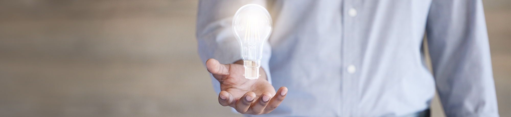 Hand with illuminated lightbulb hovering over it